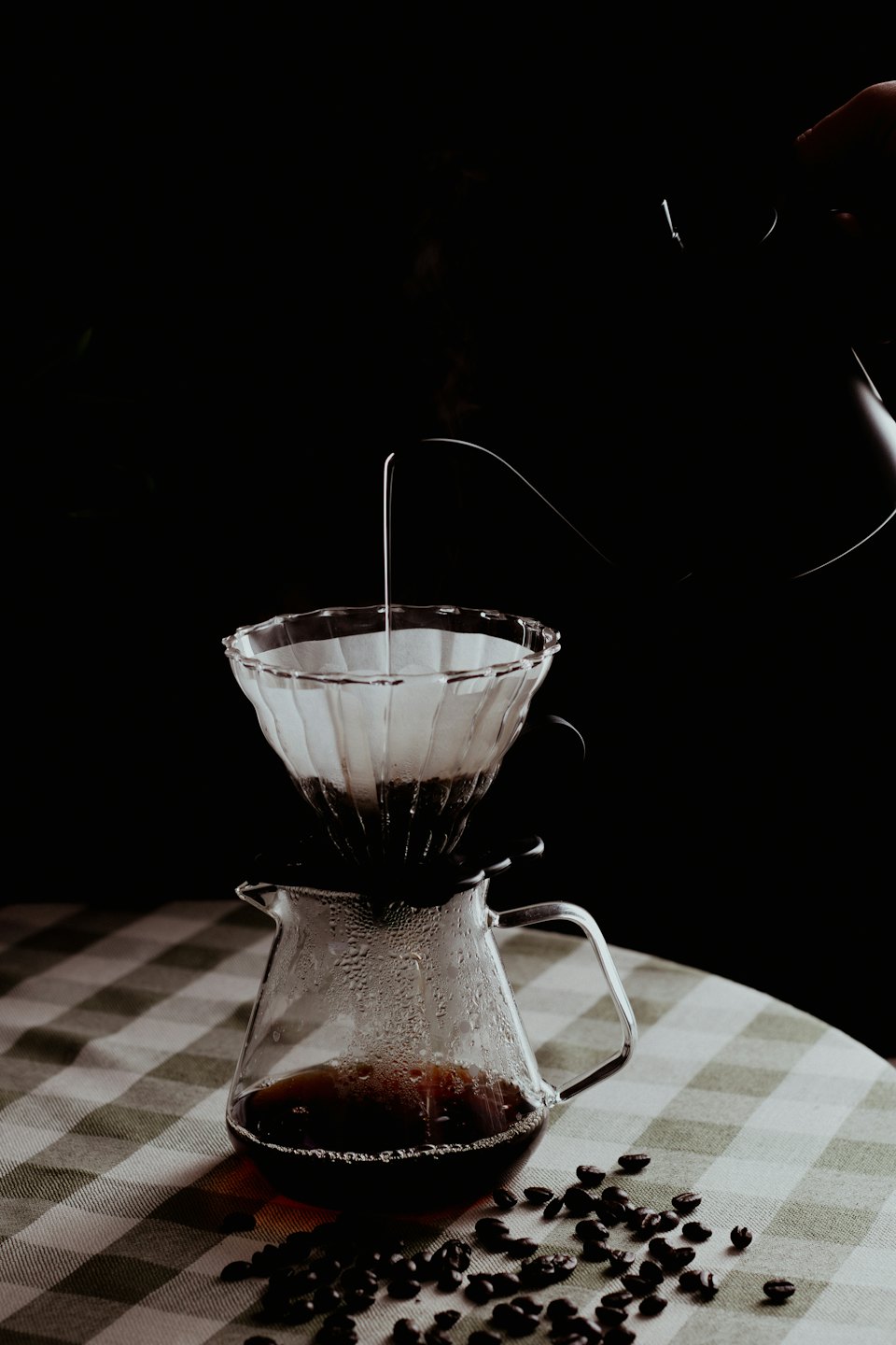 Håndbrygging av kaffe med hellekanne og glassfilter.