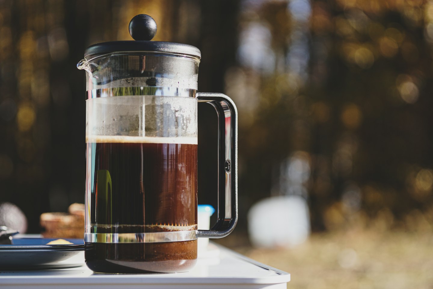 En presskanne med kaffe står på et utendørsbord.