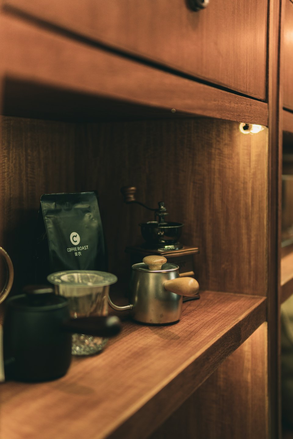 Kaffebryggeutstyr og kaffebønner arrangert på en trehylle.