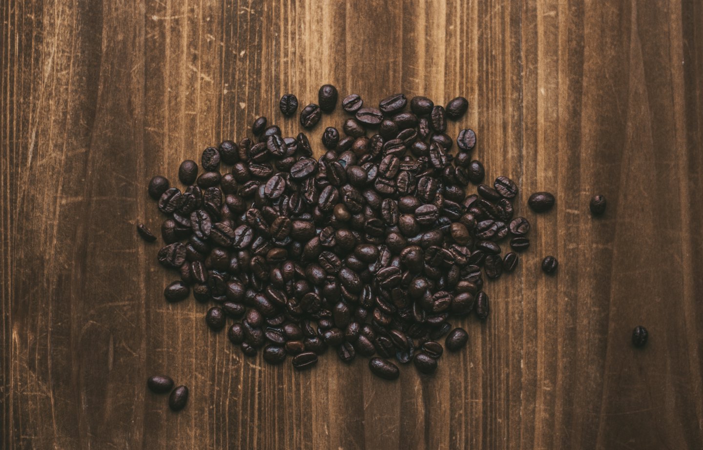 Mørkbrente kaffebønner stablet på en treoverflate.